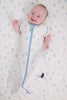 Baby in a blue dot clevasleep dreamsuit on a polka dot background in a cot.